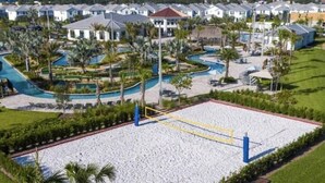 Un complexe hôtelier doté d’un grand terrain de beach-volley sablonneux, de palmiers et d’un espace piscine.