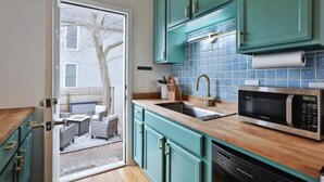 A kitchen with teal cabinets, a sink, a microwave, and a dishwasher. - 3rd Ave Cottage - Close to Short North & Downtown (Columbus)