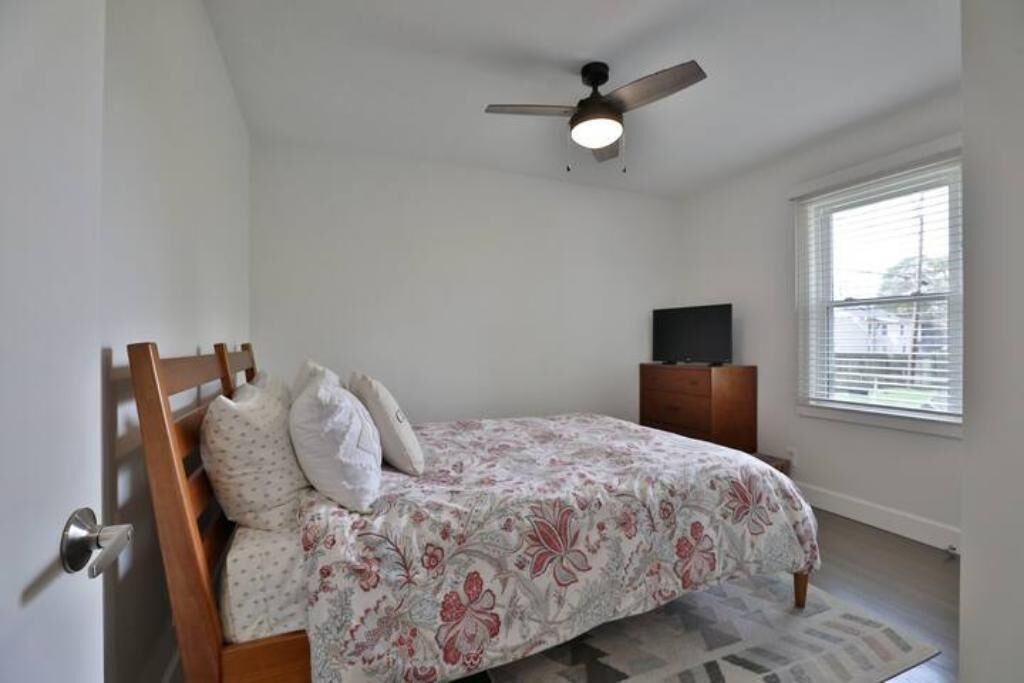 Ein Schlafzimmer mit Bett, Deckenventilator, Fernseher und Fenster.