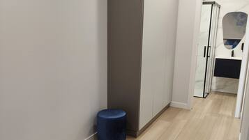 Una habitación de hotel moderna con un armario grande, un taburete redondo pequeño y una alfombra azul en el suelo.