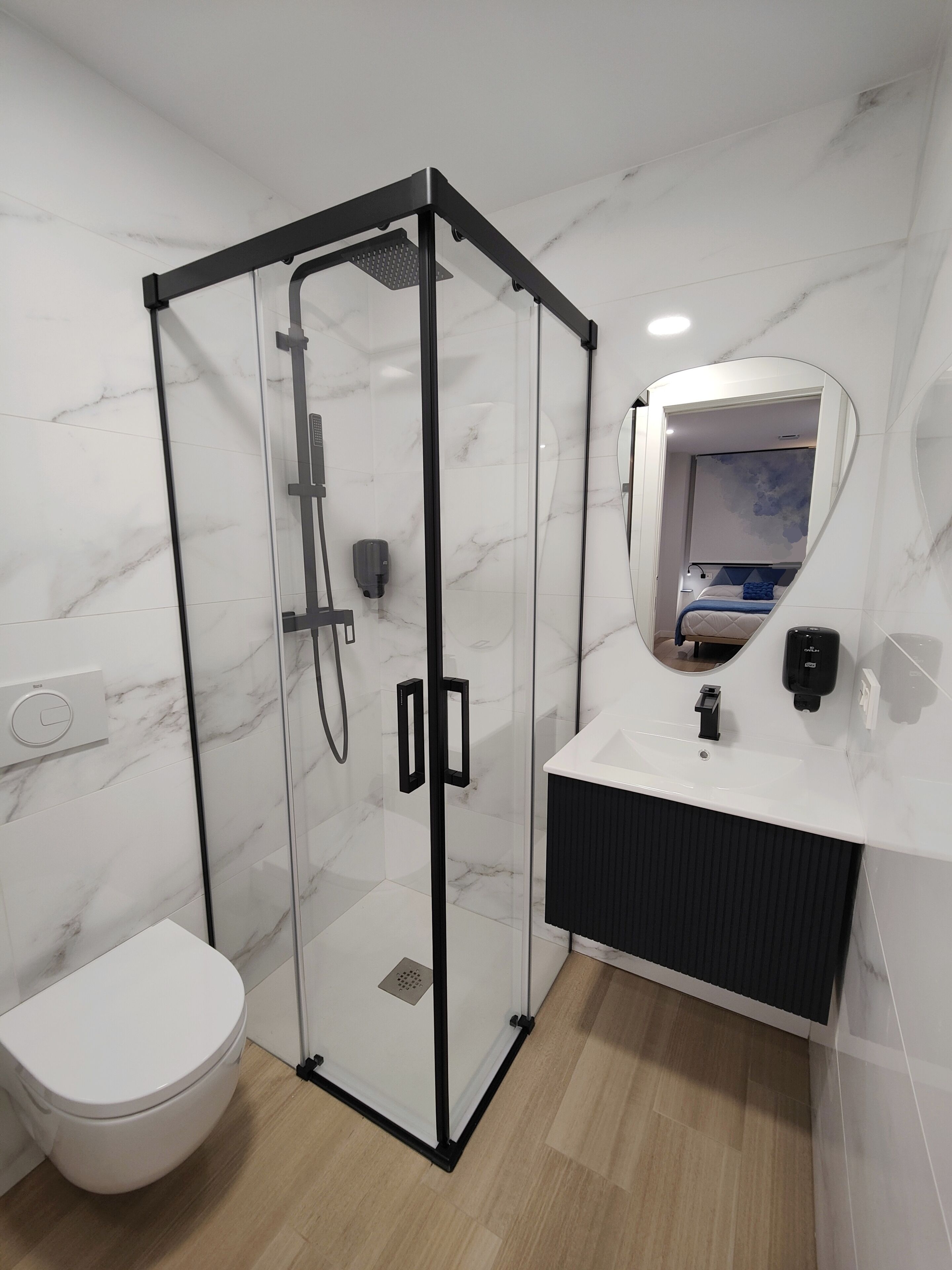 Un baño moderno con ducha separada por mamparas de vidrio, inodoro blanco y tocador con espejo.