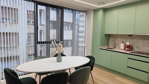A modern kitchen with green cabinets, a white countertop, and a vase with dried flowers on the table. - Elegancia y Modernidad en el Punto más Céntrico de Oviedo (Oviedo)