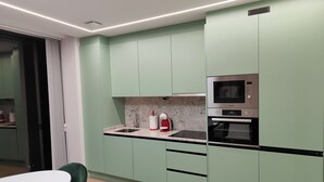 A modern kitchen with green cabinets, a microwave, and an oven. - Elegancia y Modernidad en el Punto más Céntrico de Oviedo (Oviedo)