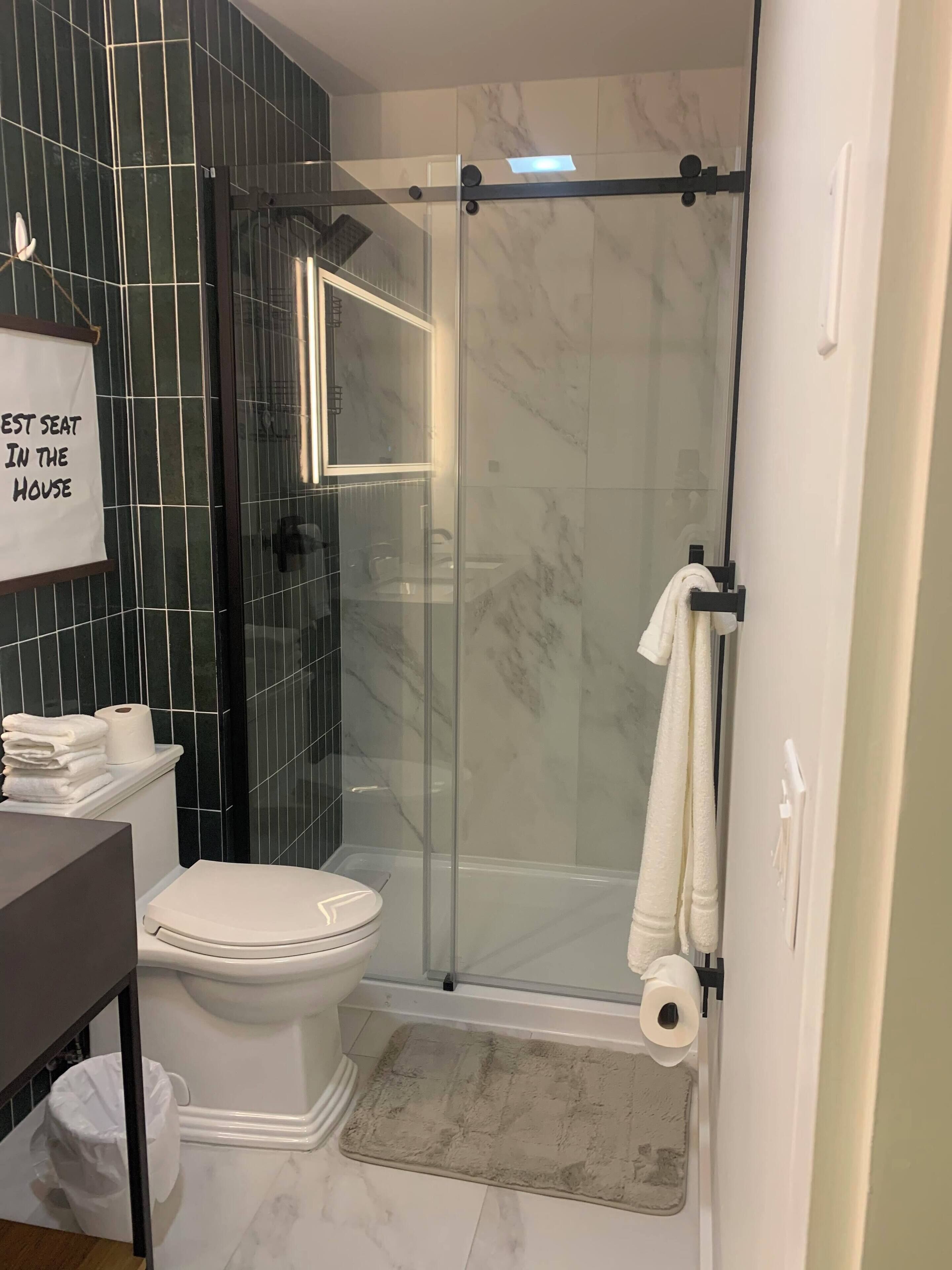A bathroom with a glass-enclosed shower, a toilet, a sink, and a towel rack.