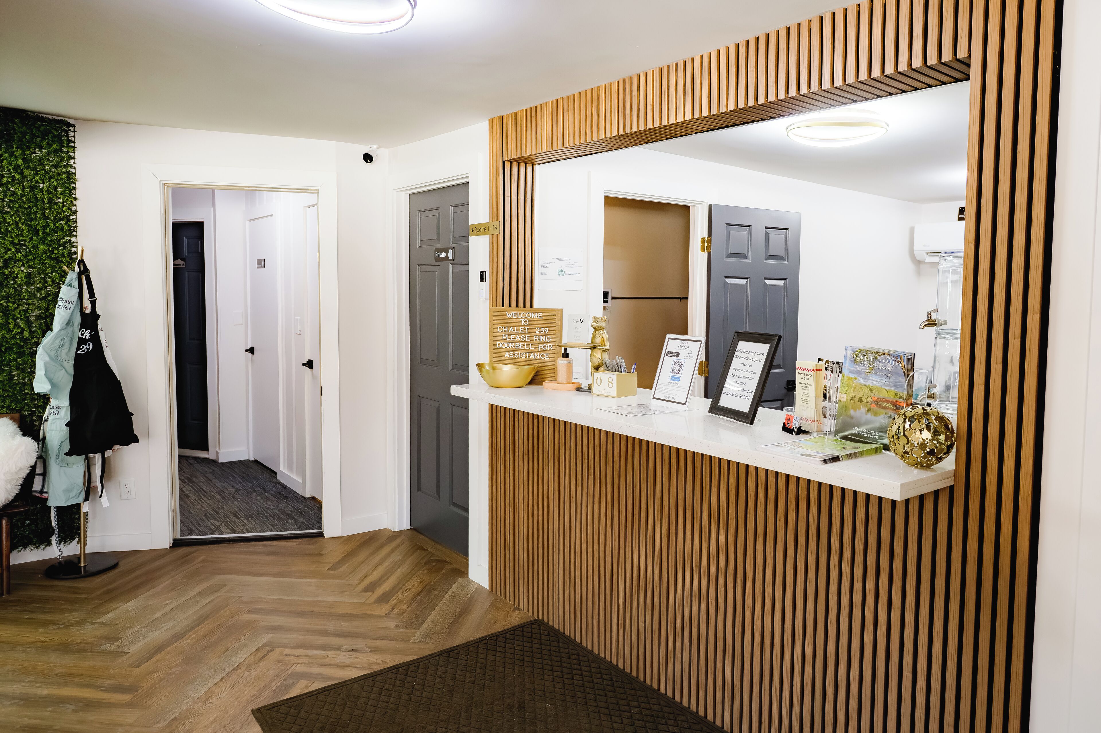 Un área de recepción con paneles de madera, mostrador de recepción, cartel y puerta que da a un pasillo.