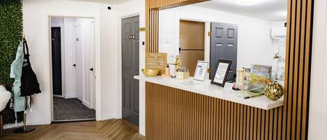 A reception area with a wooden panel design, a reception desk, a signboard, and a door leading to a hallway.