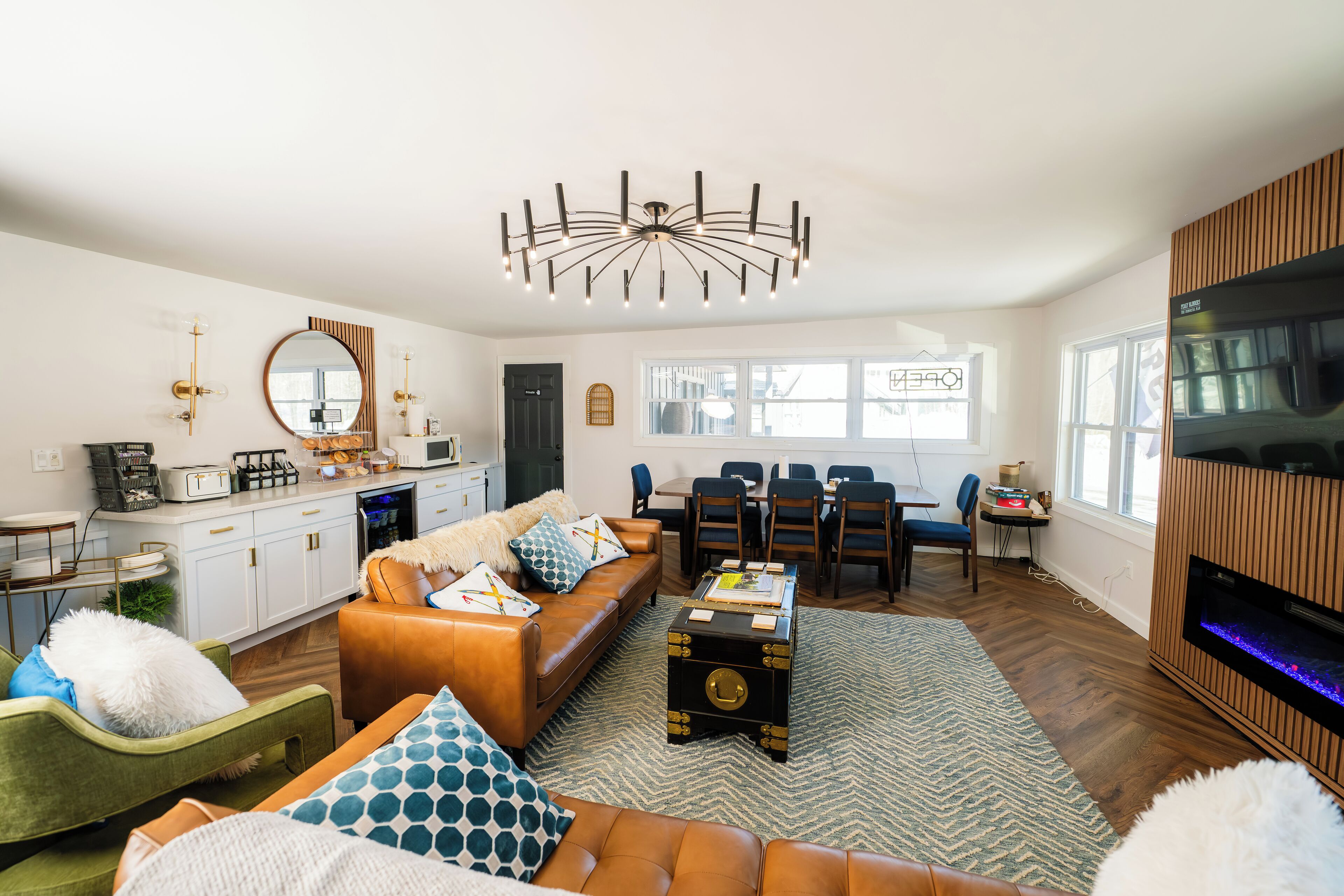 A modern living room with a sofa, a coffee table, a fireplace, and a dining area.