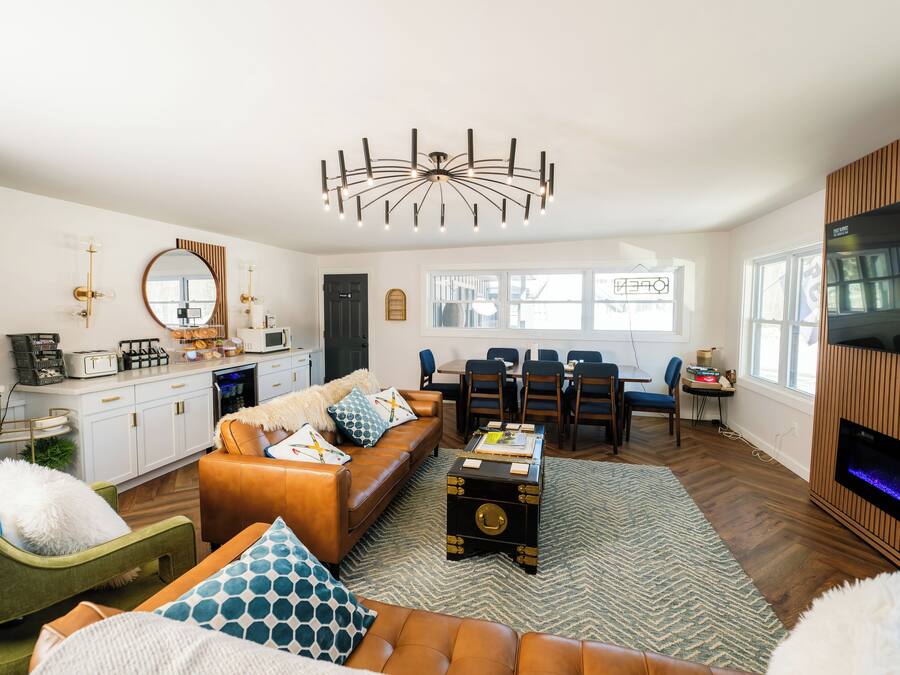 A modern living room with a sofa, a coffee table, a fireplace, and a dining area.