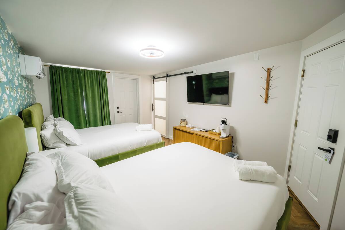 A hotel room with two beds, a desk, a TV, and a coat rack.