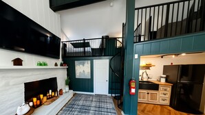 A modern kitchen with a built-in stove, a refrigerator, and a sink. There is a staircase leading to an upper level. - Chalet 239 (West Dover)