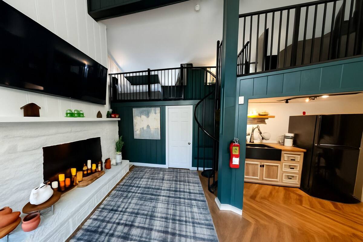 A modern kitchen with a built-in stove, a refrigerator, and a sink. There is a staircase leading to an upper level.