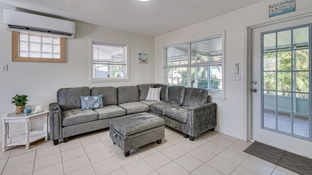 Una sala de estar con un sofá modular, una mesita auxiliar y una puerta con vistas a palmeras.