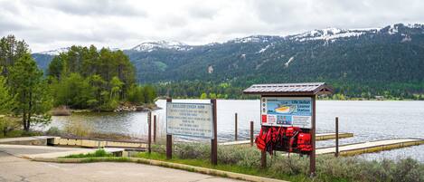 A lakeside parking area with a life jacket station and informational signs.