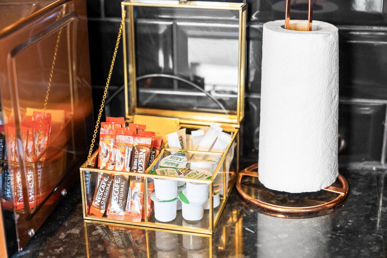 A kitchen counter with a coffee maker, a box of coffee pods, and a roll of paper towels.