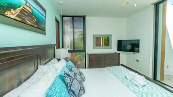 Habitación de hotel con una cama grande, televisión de pantalla plana, cómoda y ventana con persianas.