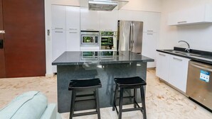Cozinha moderna com ilha central, eletrodomésticos de aço inoxidável e forno embutido.