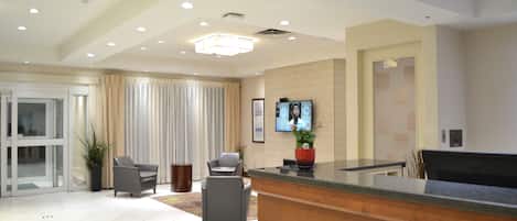 A modern reception area with a reception desk, seating area, and a television screen.