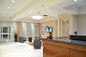A modern reception area with a reception desk, seating area, and a television screen.