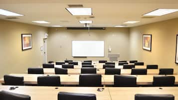 A conference room with multiple tables and chairs, a whiteboard, and ceiling lights.