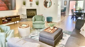 Ein geräumiges Wohnzimmer mit Kamin, Fernseher und Essbereich mit Stühlen und Tisch.