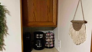 A kitchenette with wooden cabinets, a coffee maker, a mug, and a mug holder. - Convenience in Kingsford

 (Kingsford)