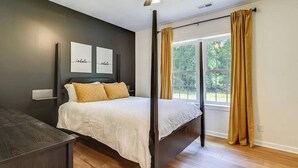 Una camera da letto con un letto, un comodino, una ventola a soffitto e una finestra con tende.