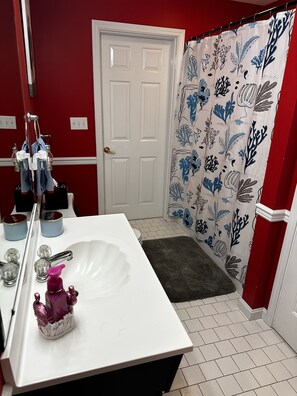 Ein Badezimmer mit einem weißen Waschbecken, einem Spiegel und einem Duschvorhang mit blau-weißem Blumendruck.