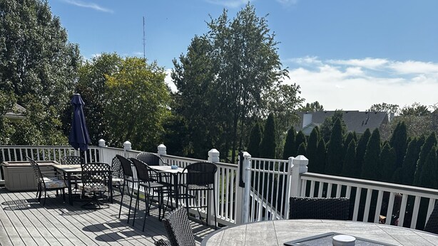 A wooden deck with outdoor furniture, including a round table and wicker chairs.