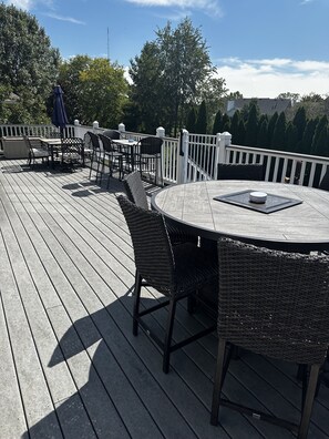 Une terrasse en bois avec des meubles d’extérieur, notamment une table ronde et des chaises en osier.