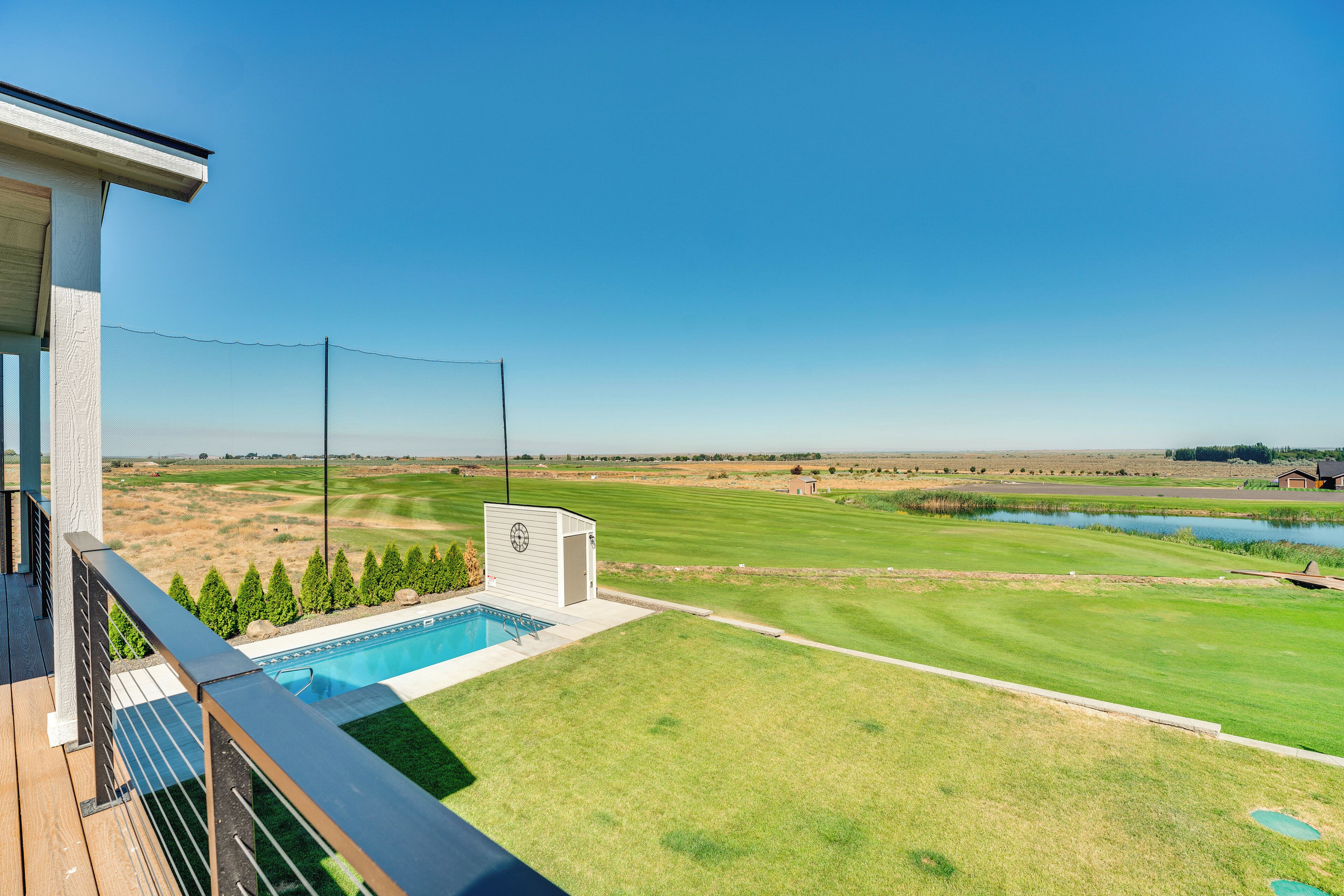 Ein Pool mit Blick auf einen Golfplatz und einen Teich.