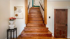 A wooden staircase with a handrail, a bust on a small table, and a door in the background. - The Golden Parlor- Historic Victorian, Hot Tub (Grass Valley)