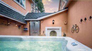 A hot tub area with a stone surround, a bicycle, and a fireplace. - The Golden Parlor- Historic Victorian, Hot Tub (Grass Valley)