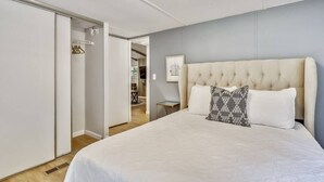 A bedroom with a large bed, a wardrobe, and a small table. - The Farmer's Cottage at Kings Crossing (Fredericksburg)