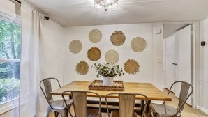 A dining area with a wooden table and metal chairs, surrounded by decorative wall art. - The Farmer's Cottage at Kings Crossing (Fredericksburg)