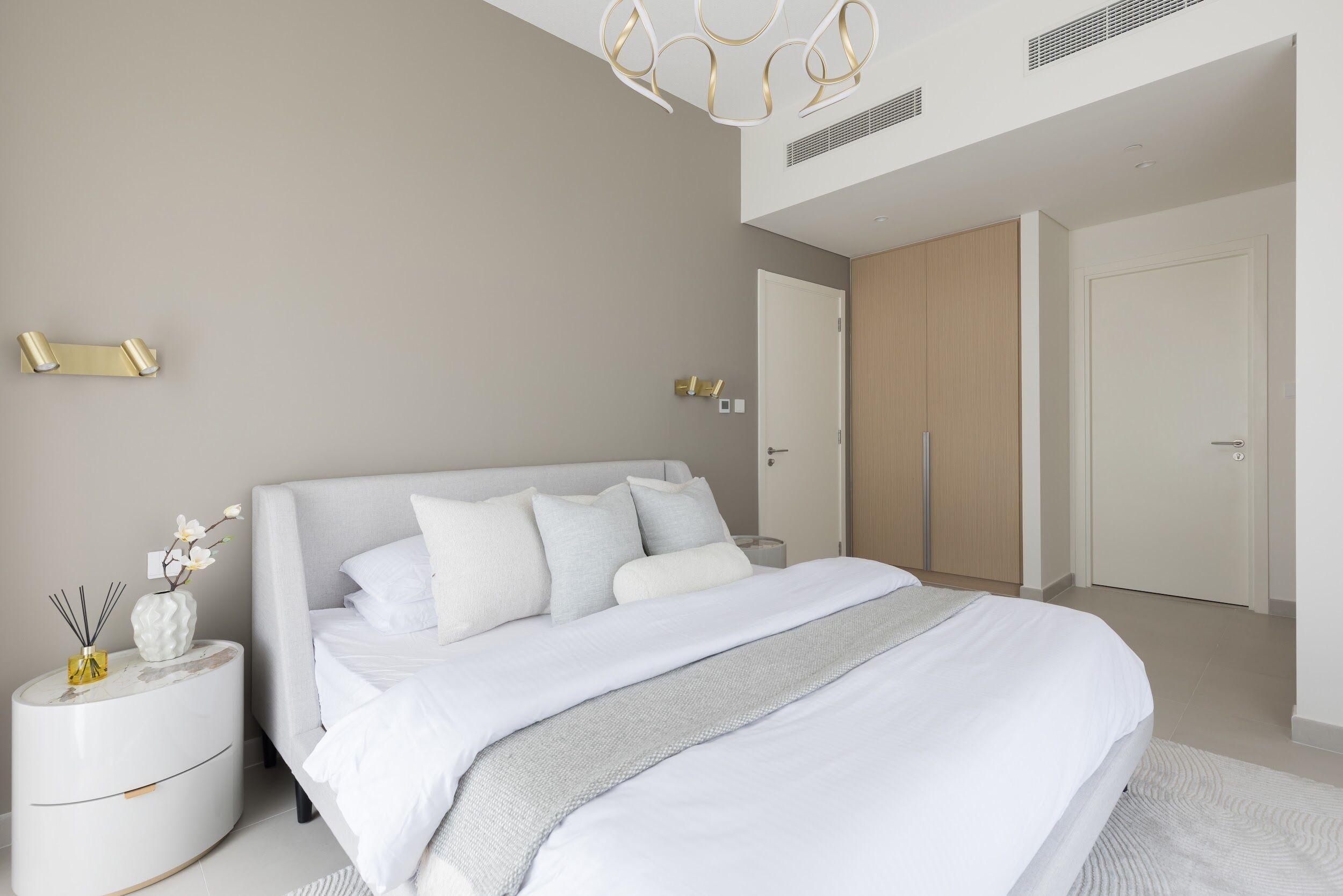 Une chambre à coucher moderne avec un grand lit, des tables de chevet et une armoire.
