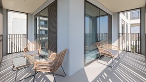A modern balcony with wicker chairs and a glass table, large glass doors, and a view of the surrounding area. - Creek Beach Roomy 3BR with terrace (Dubai)
