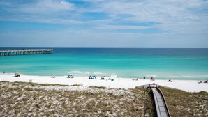 A beach with a wooden boardwalk leading to the shore, clear turquoise water, and a pier in the background. - Relax in 409...Get in a Flip-Flop State of Mind (Navarre)