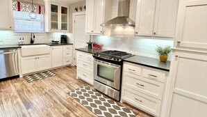Una cocina moderna con armarios blancos, una estufa de acero inoxidable y una alfombra estampada.
