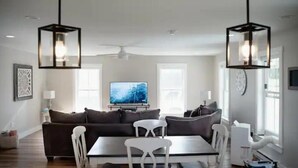 A modern living room with a dark sofa, white chairs, a glass coffee table, and a flat-screen TV. - Luxury on Seneca Wine Trail, 3 King Beds with Awesome Country View (Watkins Glen)