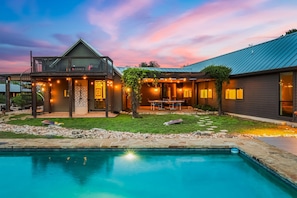 Uma casa de dois andares com piscina, área de estar ao ar livre e luzes de Natal.