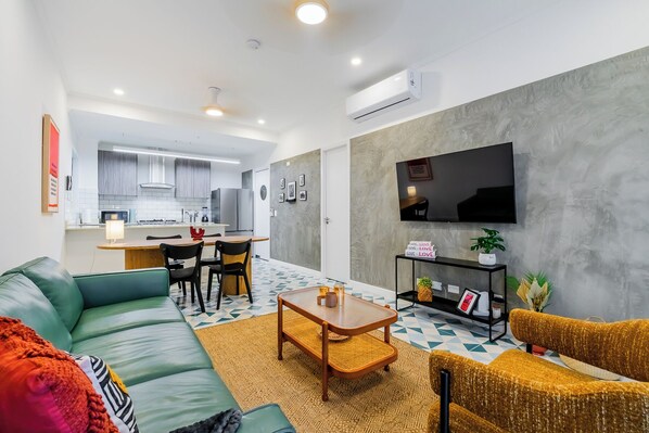 A modern living room with a sofa, a coffee table, and a TV mounted on the wall. - Casa Quijano 06 By Wynwood House (Panama City)