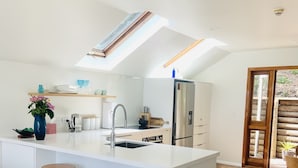 Una cocina moderna con una isla central, armarios blancos y un tragaluz.