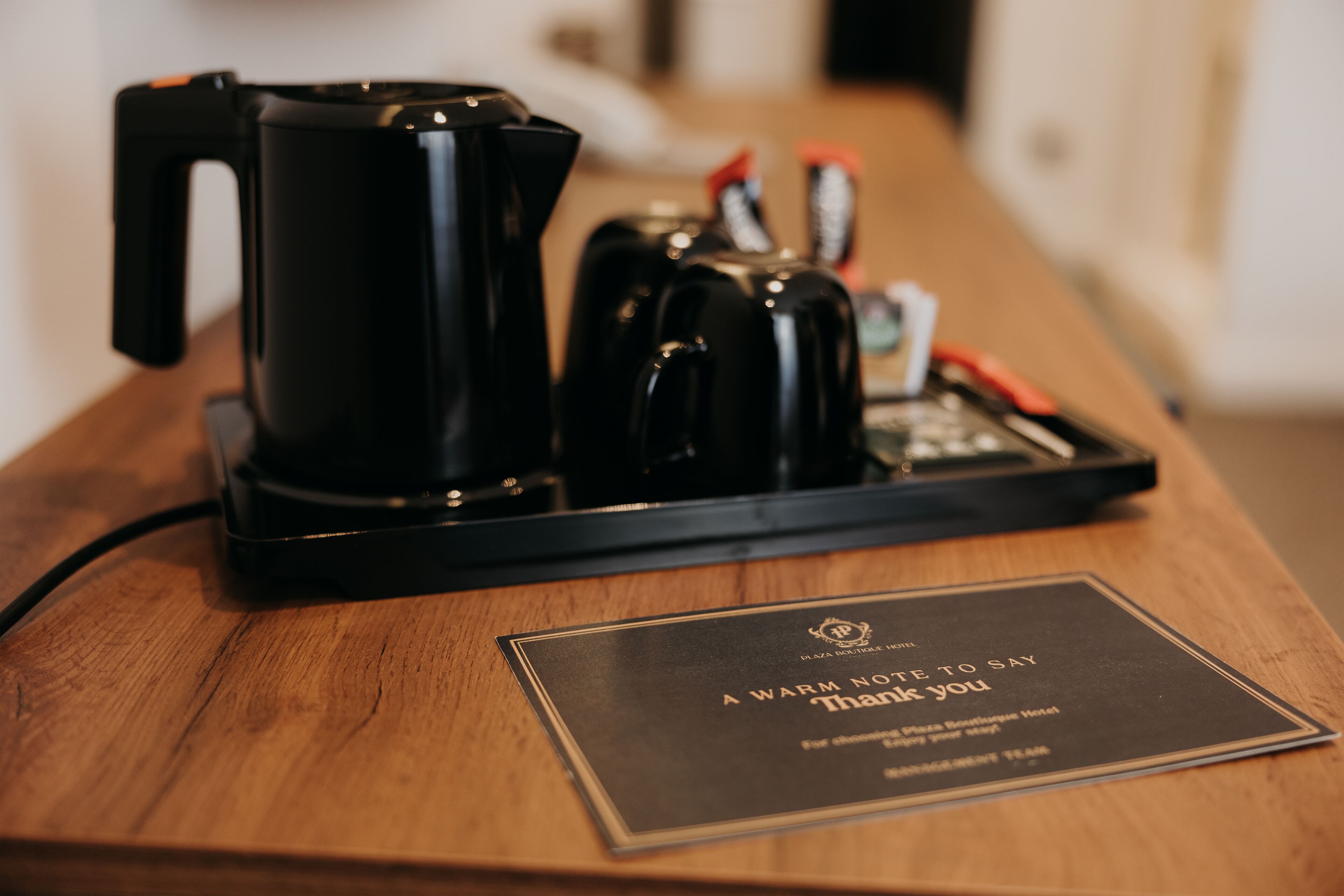 A coffee maker and a tray with a thank you sign on a wooden table.