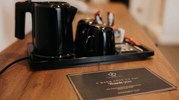 A coffee maker and a tray with a thank you sign on a wooden table.