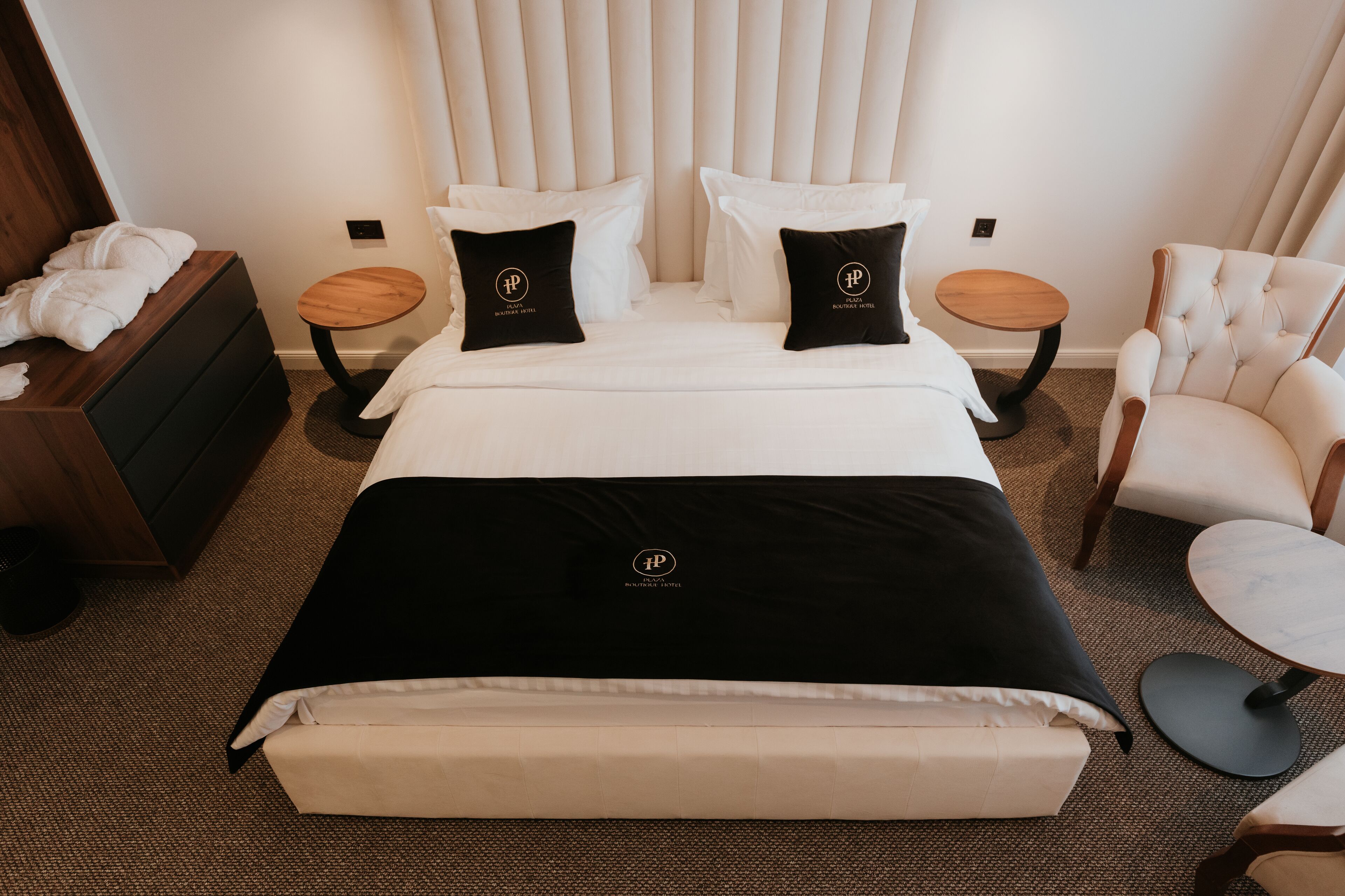 Een hotelkamer met een groot bed, twee nachtkastjes, een stoel en een dressoir.