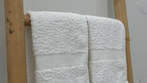Un baño con un perchero de madera que sostiene tres toallas blancas.