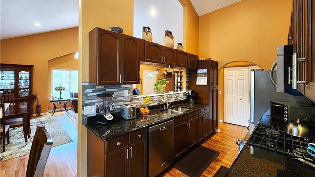 Una cocina moderna con armarios de madera oscura, horno empotrado y una isla grande con pileta.
