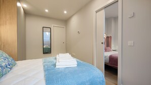 Un dormitorio con cama, espejo, puerta y un interruptor de luz.