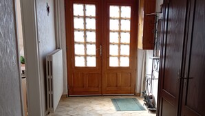 Un passadís amb una porta de fusta, un radiador i un terra enrajolat.