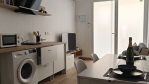 Una cocina moderna con lavadora, microondas y comedor con una mesa lista para dos.